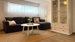 A living room with a dark sofa, a white coffee table, and a glass cabinet. - Captain's House Apartment 2 (Cuxhaven-Duhnen)