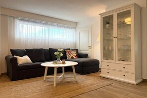 A living room with a dark sofa, a white coffee table, and a glass cabinet. - Captain's House Apartment 2 (Cuxhaven-Duhnen)