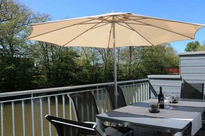 Un patio con tavolo e sedie, un ombrellone e una bottiglia di vino.