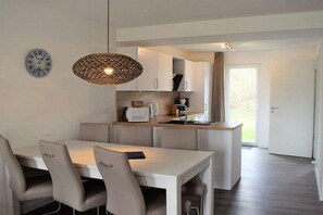 Una cucina moderna con mobili bianchi, un tavolo da pranzo con sedie e una lampada a sospensione.