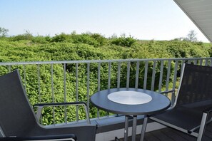Un balcone con un tavolo rotondo e due sedie, affacciato su un paesaggio verdeggiante e rigoglioso.