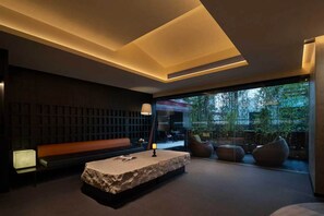 Un interior moderno con un banco de piedra, una zona de estar y vistas a través de un muro de cristal.