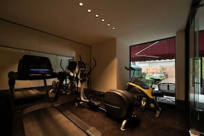 Un gimnasio con equipamiento de cardio, una cinta de correr y una bicicleta estática.