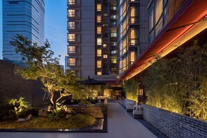 A modern building with multiple floors, outdoor seating area, and a well-maintained garden. - YuFei Hotel (Guangzhou)