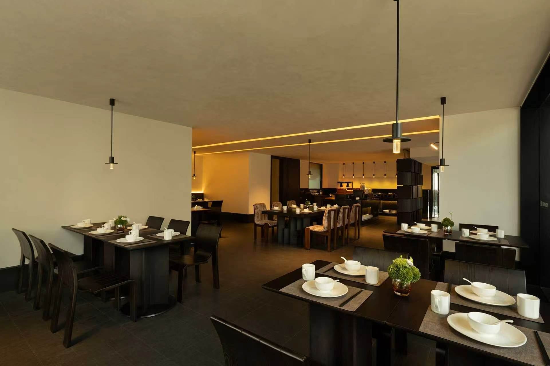 Un comedor moderno con varias mesas, sillas e iluminación colgante.