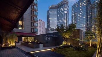 A modern urban courtyard with a seating area, a water feature, and tall buildings in the background.