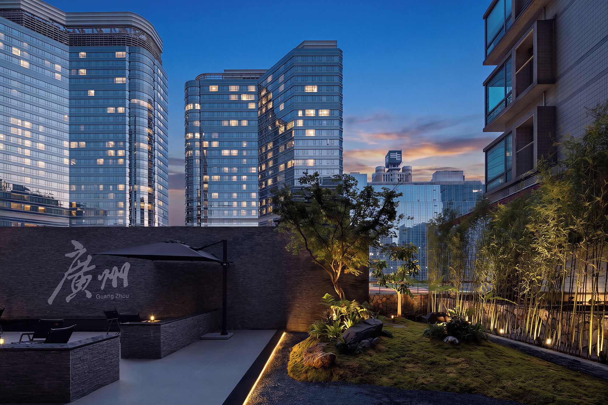 Eine moderne Stadtlandschaft mit Hochhäusern, einer begrünten Gartenanlage mit Steinen und Pflanzen sowie einer Sitzgelegenheit mit Bank und Tisch.