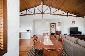 A spacious living area with a wooden dining table, a sofa, and a television. - Ocean-view 3-bed House in Halls Head (Perth)