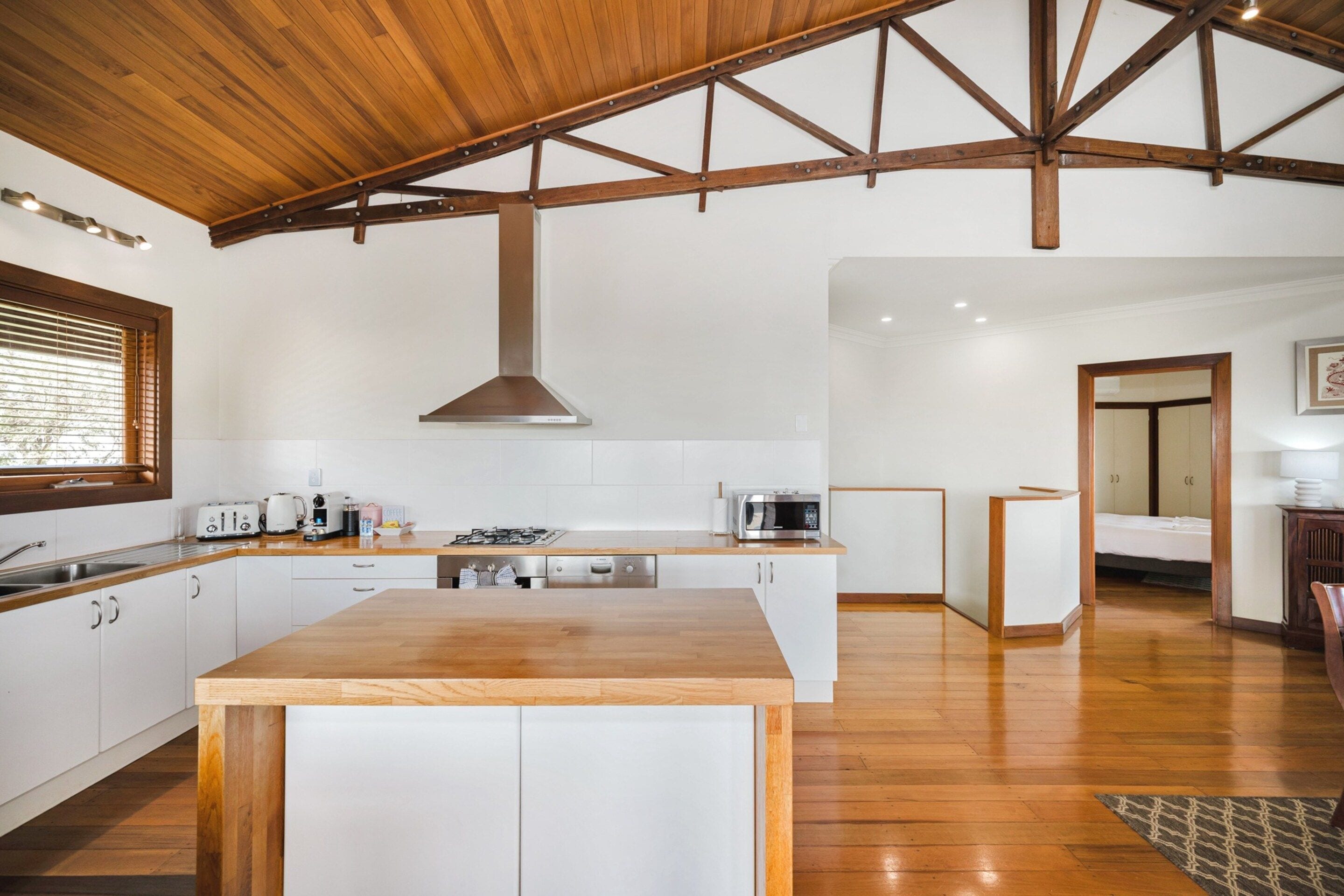 Una cocina amplia con vigas de madera, una isla grande y electrodomésticos modernos.