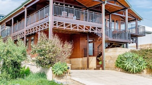 Ein zweistöckiges Holzhaus mit Balkon, Steinmauer und gepflegtem Garten.