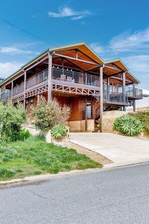 A two-story wooden house with a balcony, a stone wall, and a well-maintained garden. - Ocean-view 3-bed House in Halls Head (Perth)
