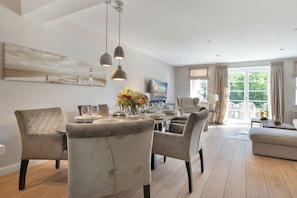 A dining area with a table set for four, surrounded by upholstered chairs. - Holiday home in Sylt with 3 bedrooms (Westerland)