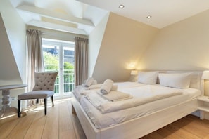 A bedroom with a large bed, a chair, a desk, and a window with curtains. - Holiday home in Sylt with 3 bedrooms (Westerland)