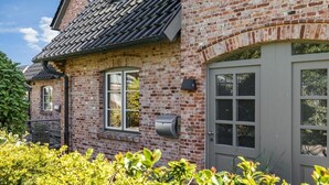 Una casa de ladrillo con una puerta gris, una ventana y un buzón.