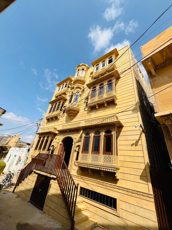 A multi-story building with ornate architectural details, a staircase, and a gated entrance.