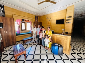 A hotel lobby with a check-in counter, a seating area with a bench, and a patterned floor.