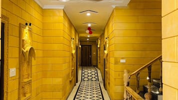 A hallway with yellow walls, a black and white patterned floor, and a ceiling fan.
