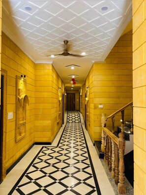 A hallway with yellow walls, a black and white patterned floor, and a ceiling fan.