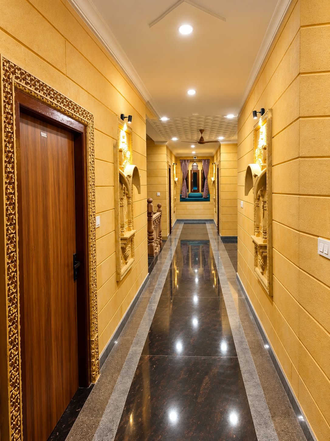 A hotel hallway with a wooden door, wall sconces, and a blue carpeted area.