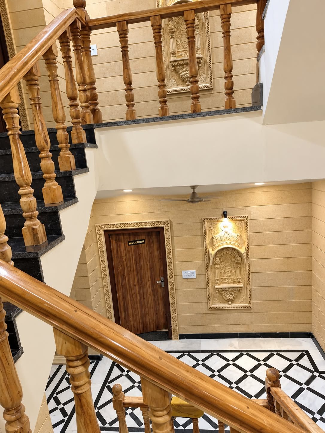 Un interior de varios niveles con una escalera de madera, un aseo y una pared decorativa.