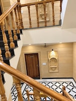 Un interior de varios niveles con una escalera de madera, un aseo y una pared decorativa.
