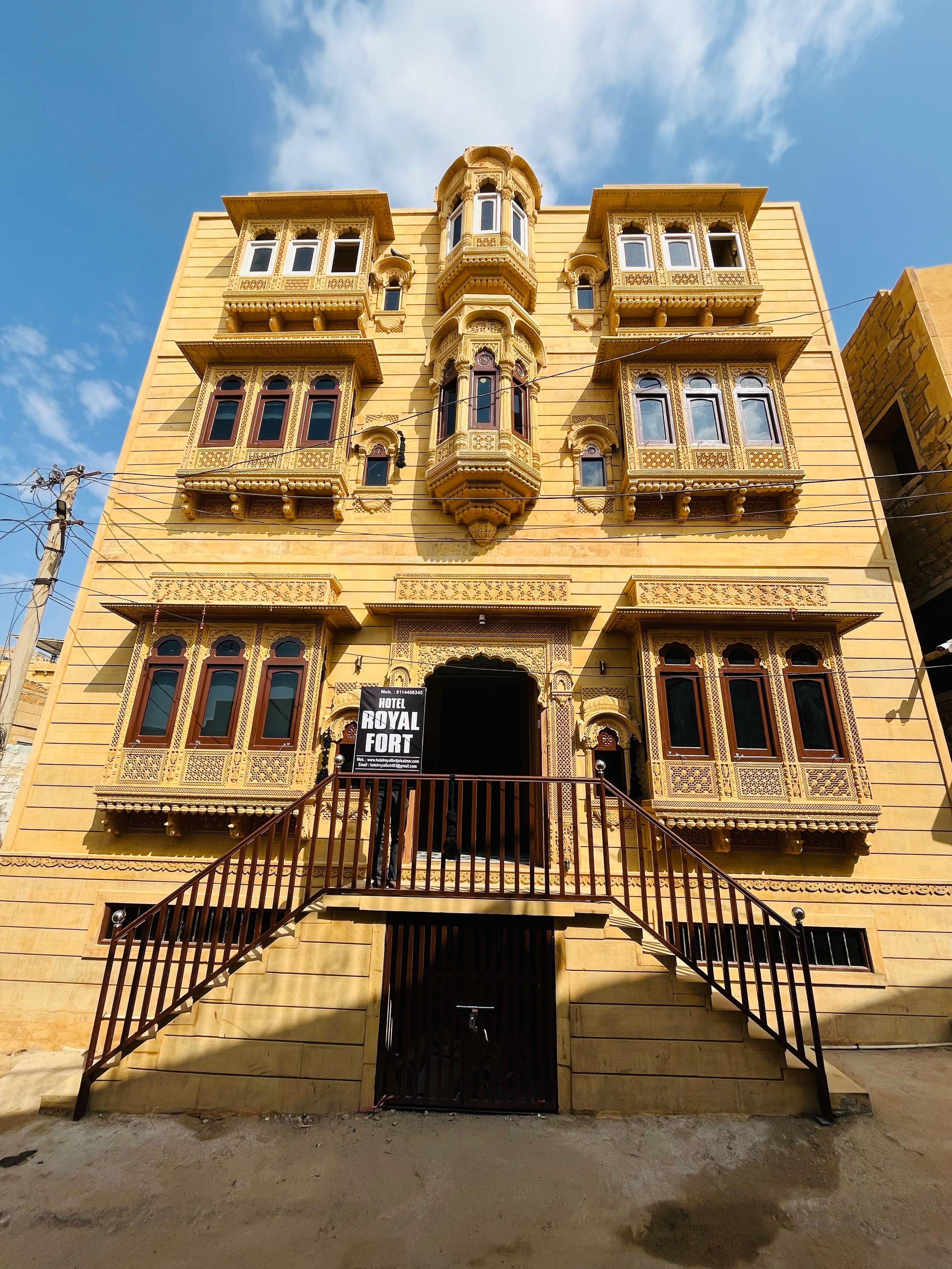 Un hotel de estilo arquitectónico tradicional, con balcones ornamentados y un cartel.