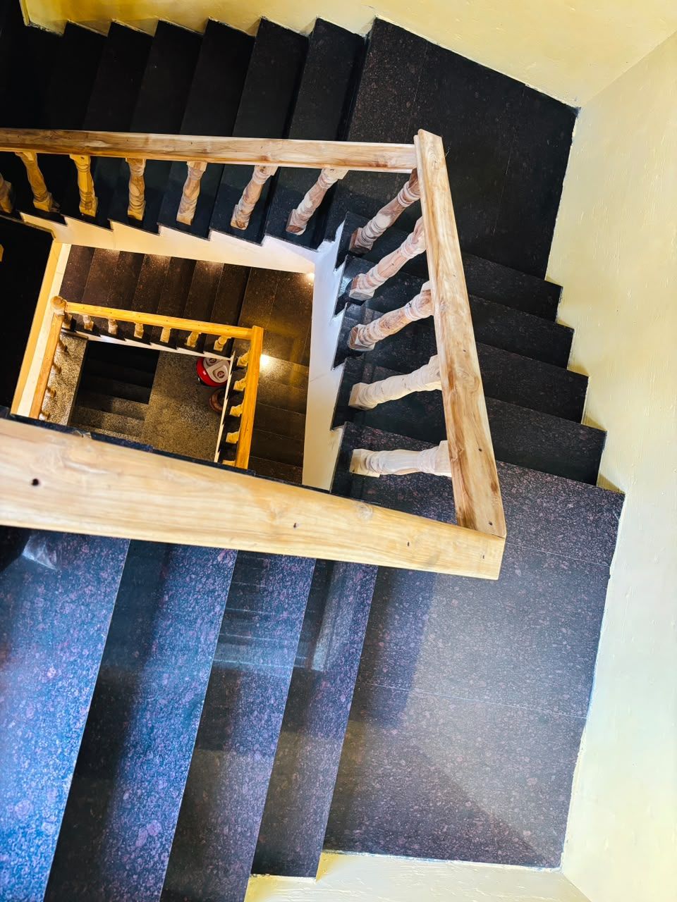 A spiral staircase with a wooden handrail and black steps.