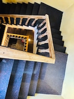 Una escalera de caracol con barandilla de madera y escalones negros.