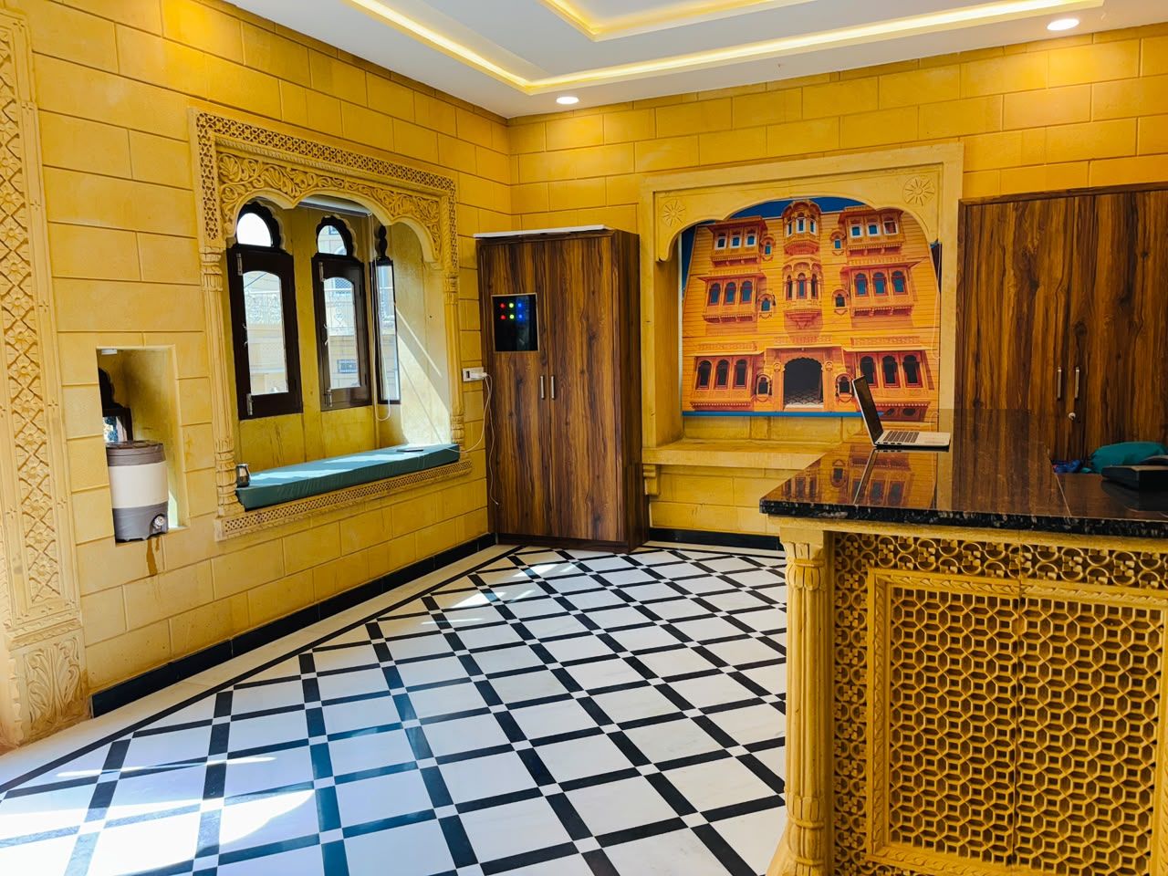 A hotel lobby with a check-in counter, a seating area with a bench, and a patterned floor.
