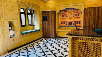 A hotel lobby with a check-in counter, a seating area with a bench, and a patterned floor.