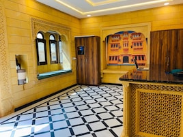Un vestíbulo de hotel con mostrador de recepción, una zona de estar con un banco y un suelo estampado.