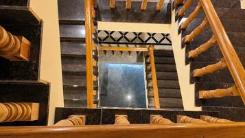 Una escalera de madera con barandilla de diseño geométrico y un espejo que refleja la escalera.