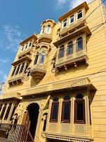 Un edificio de varios pisos con detalles arquitectónicos ornamentales, incluyendo balcones y ventanas labradas.