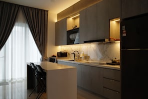 A modern kitchen with a marble countertop, built-in appliances, and a dining area with chairs.
