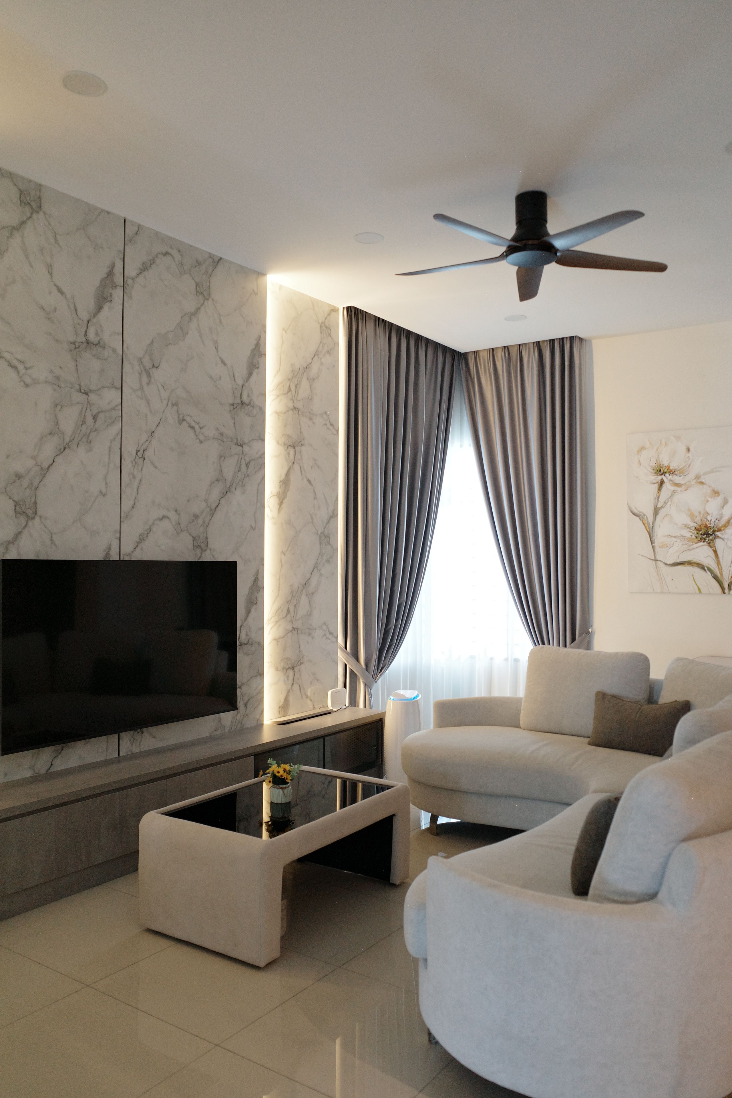 Una sala de estar moderna con una televisión de pantalla plana, un ventilador de techo, un sofá y una mesa de centro.