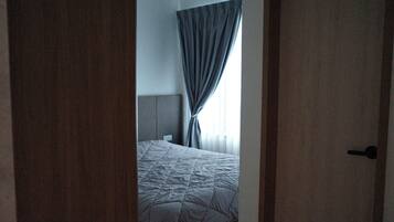 Un dormitorio con cama, cortinas y una puerta.