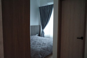 A bedroom with a bed, curtains, and a door.