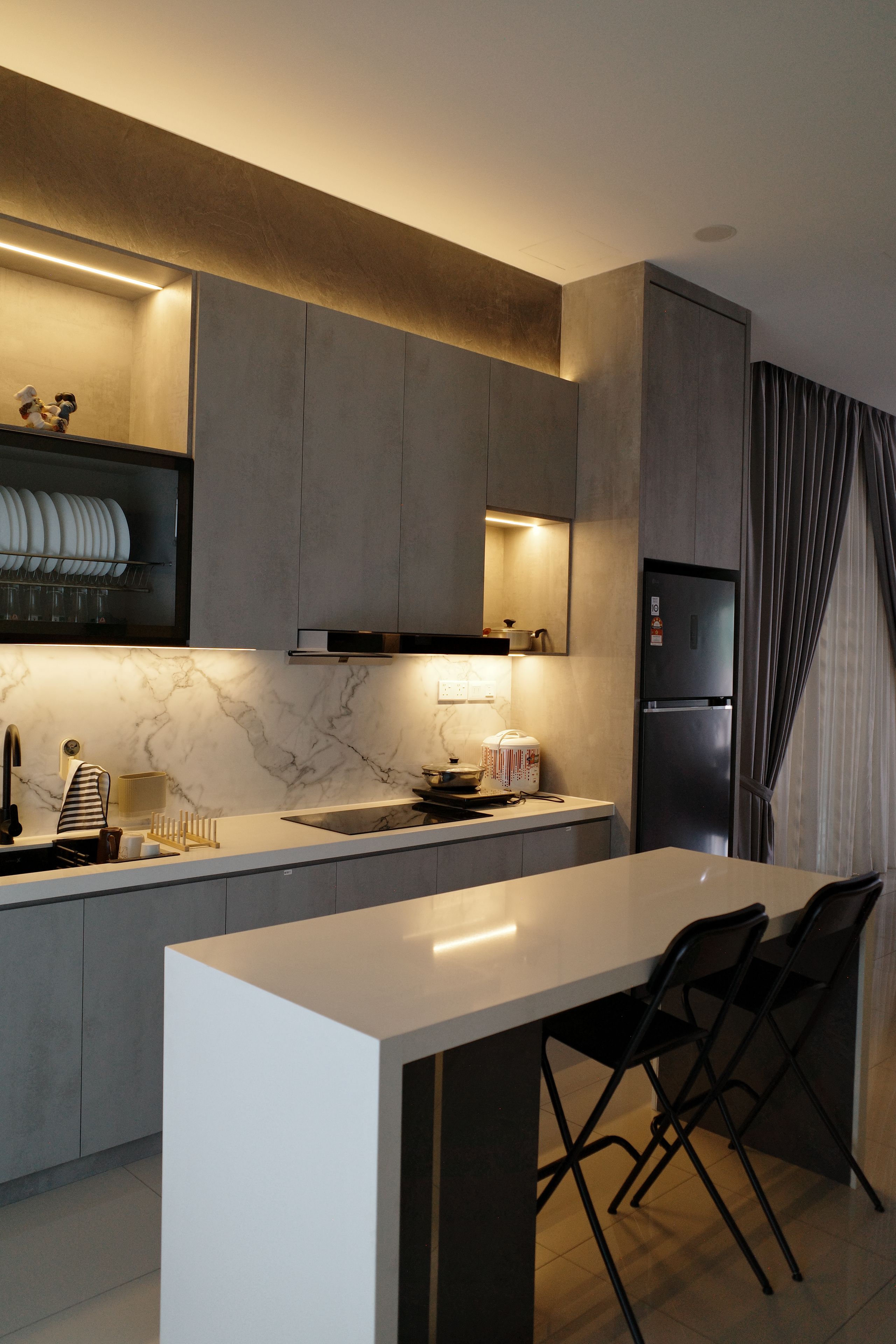 A modern kitchen with a marble countertop, a built-in oven, and a refrigerator.