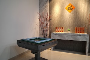 A room with a billiards table, a wooden wall with a hanging sign, and a display of framed items.