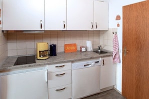 A kitchen with white cabinets, a coffee maker, a toaster, and a dish rack. - Holiday apartment with 2 bedrooms (Cuxhaven)
