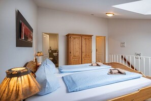 Ein Schlafzimmer mit Bett, einem Holzschrank, einer Lampe und Blick ins Freie.