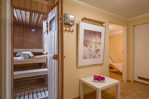 Ein Zimmer mit Sauna, einem gerahmten Bild an der Wand und einem kleinen Tisch mit rosafarbenen Gegenständen.