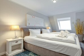 A hotel room with a bed, two bedside tables, a nightstand, a window, and a wall-mounted artwork. - Holiday apartment with 1 bedroom (Westerland)