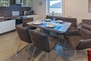A dining area with a table set for four, surrounded by four chairs. - Holiday apartment with 1 bedroom (Bensersiel)