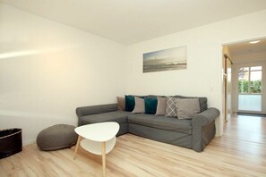 Ein modernes Wohnzimmer mit einem grauen Ecksofa, einem weißen Couchtisch und einem grauen Sitzsack.
