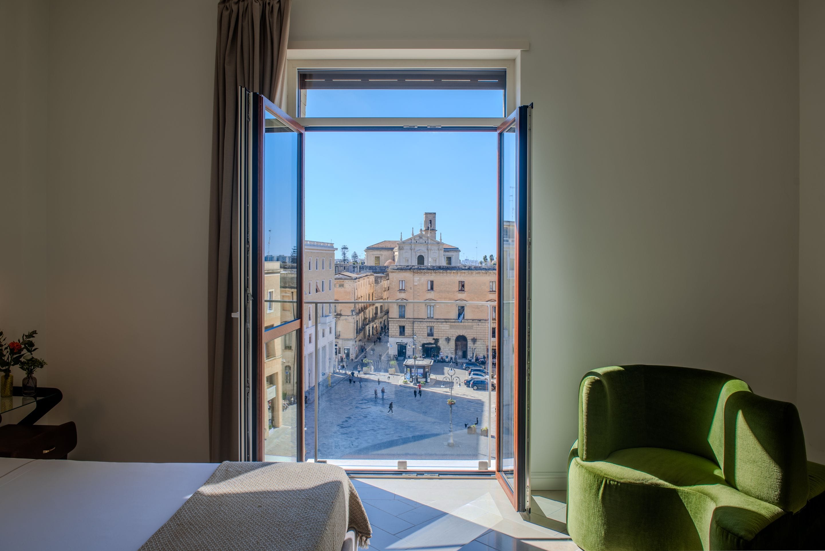 Una habitación de hotel con un ventanal grande, una silla verde y una cama.