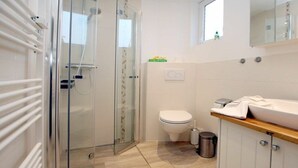 Een moderne badkamer met een douchecabine van glas, een toilet en een wastafel met een houten aanrechtblad.