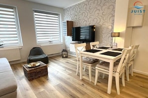 Ein modernes Wohnzimmer mit Essbereich, Fernseher und Kamin.