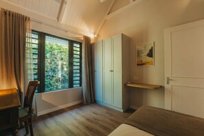 A bedroom with a bed, a desk, a chair, a wardrobe, and a window with a view of greenery. - Villa Kaz'Ana, piscine & jardin, Bain Bœuf (Cap Malheureux)