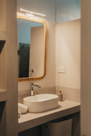 Ein Badezimmer mit einem runden Waschbecken, einem Spiegel mit goldener Rahmung und einem Handtuch auf der Ablagefläche.